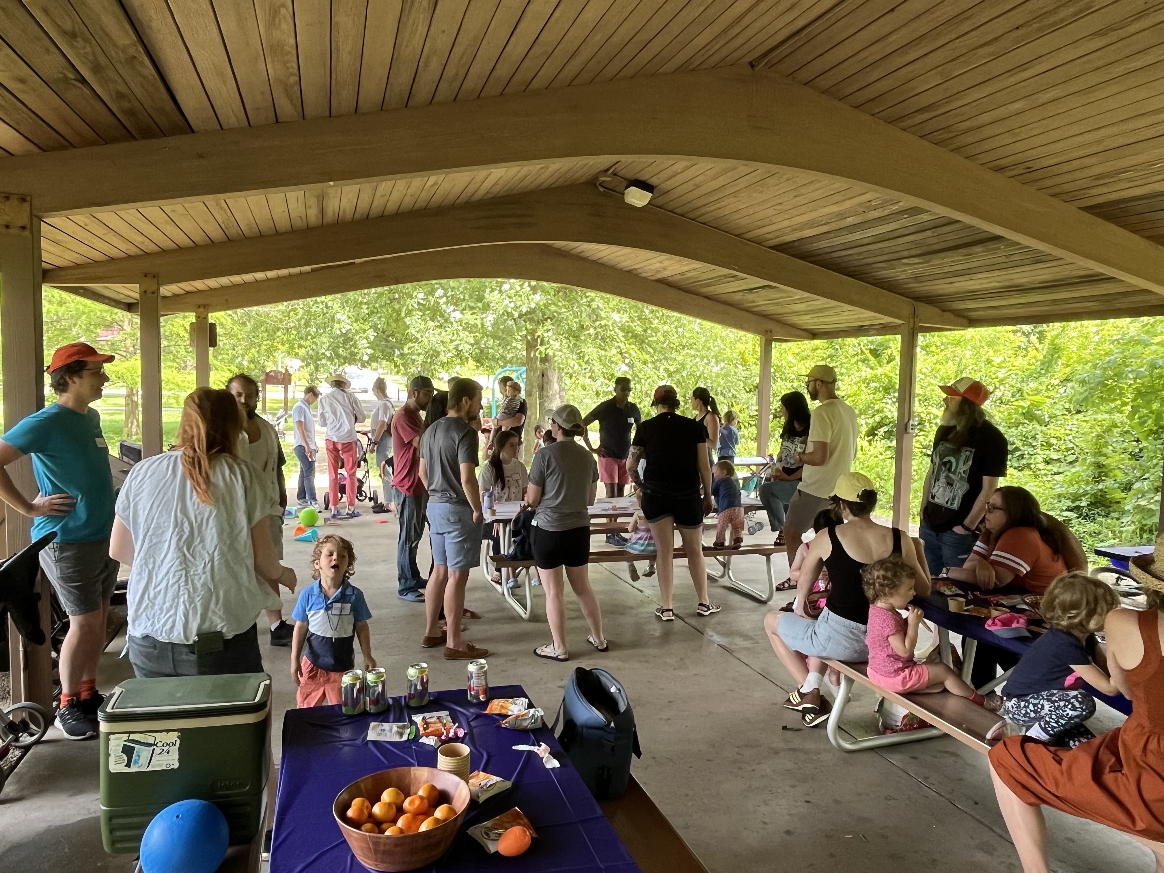People in a park shelter talking and sharing food