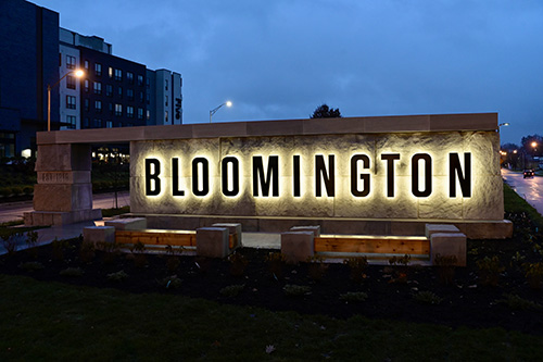 Bloomington's Bicentennial Gateway limestone wall with Bloomington letters backlighted at night