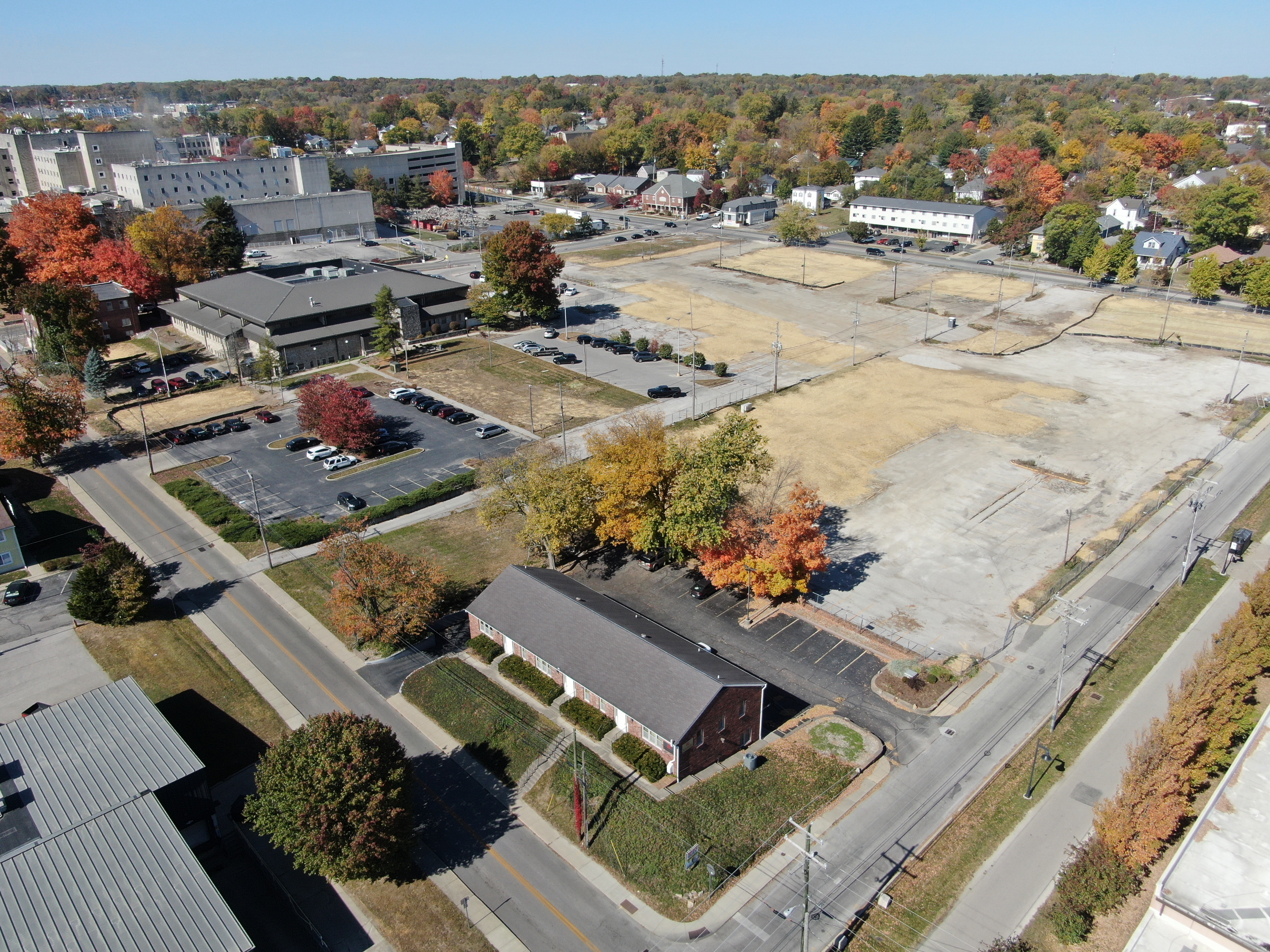Aerial drone photo showing the completed demolition work.&nbsp; The left photo is looking northwest from the intersection of 1st and Morton Street, showing a red brick office building with the site covered in straw in the background.&nbsp;